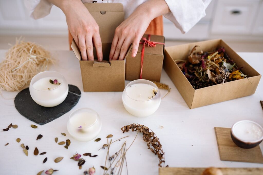 Close-up of handcrafted candles being packed with dried flowers and eco-friendly materials.